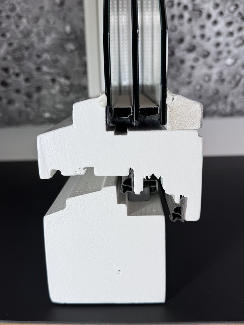 Querschnitt eines Fensterrahmens mit Isolierglas, zeigt die Schichten und Materialien in Wei&szlig; und Schwarz.