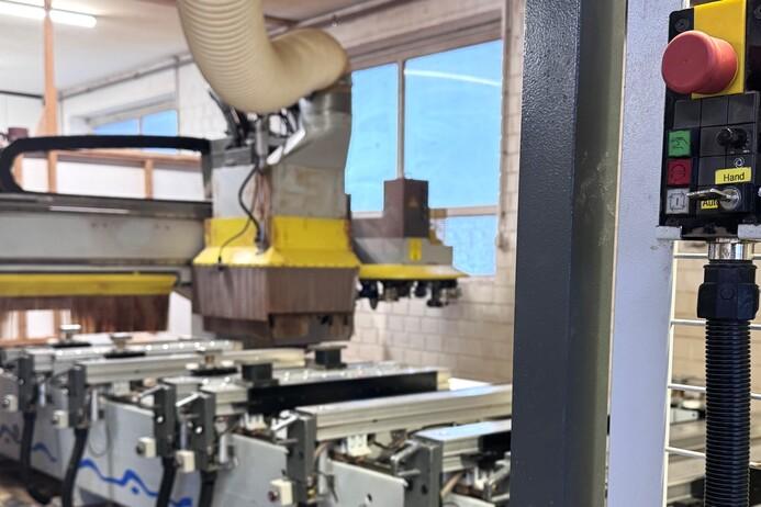 CNC-Fr&auml;se in einer Werkstatt mit Steuerkonsole und Sicht auf Maschinen im Hintergrund.