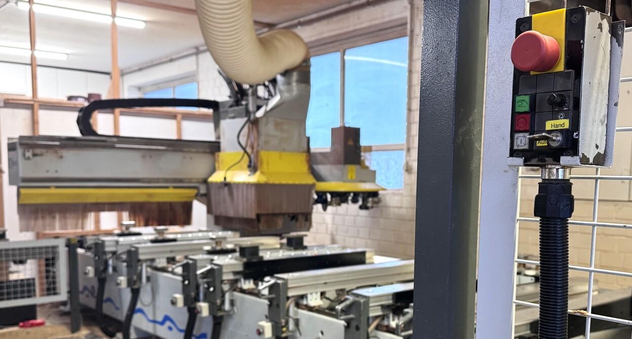 CNC-Fr&auml;se in einer Werkstatt mit Steuerkonsole und Sicht auf Maschinen im Hintergrund.