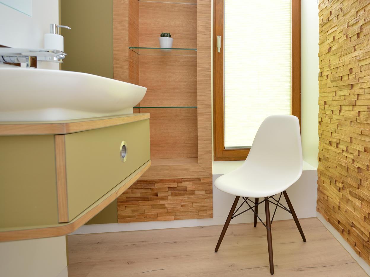 Helles Badezimmer mit Holzregal, modernem Waschbecken und wei&szlig;em Stuhl neben einem Fenster mit Jalousien.