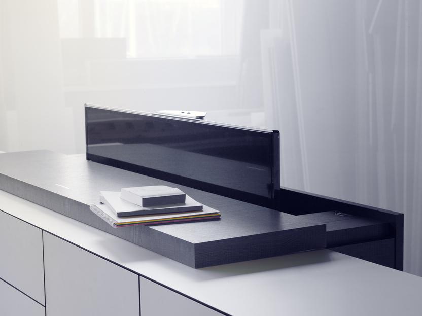 Moderne M&ouml;belanordnung mit einem schwarzen Sichtschutz auf einer Holzoberfl&auml;che und gestapelten Notizbl&ouml;cken.