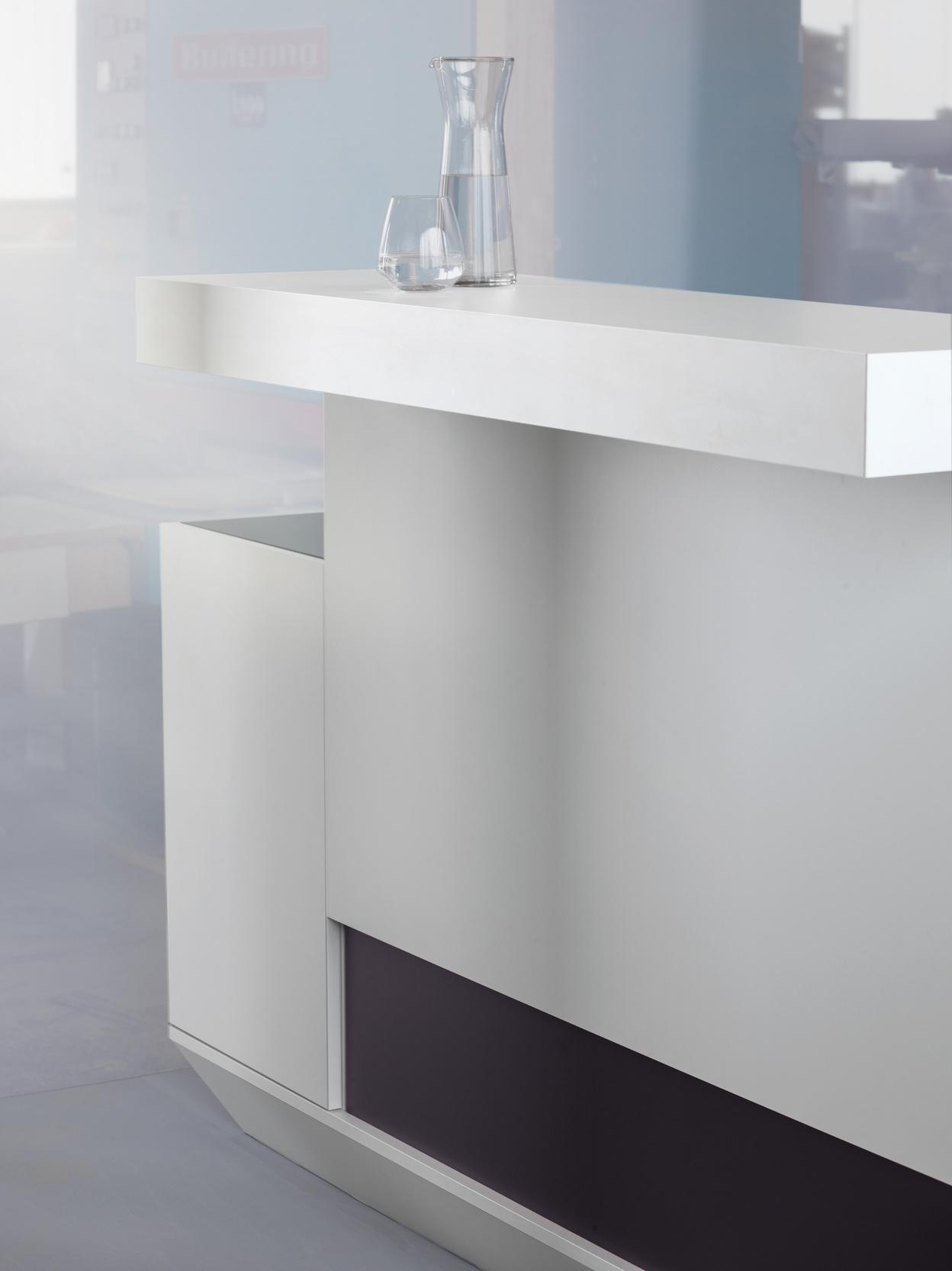 Moderne Bar mit einem wei&szlig;en Tisch und einer Glaskaraffe sowie einem Glas auf der Oberfl&auml;che. Minimalistisches Design.