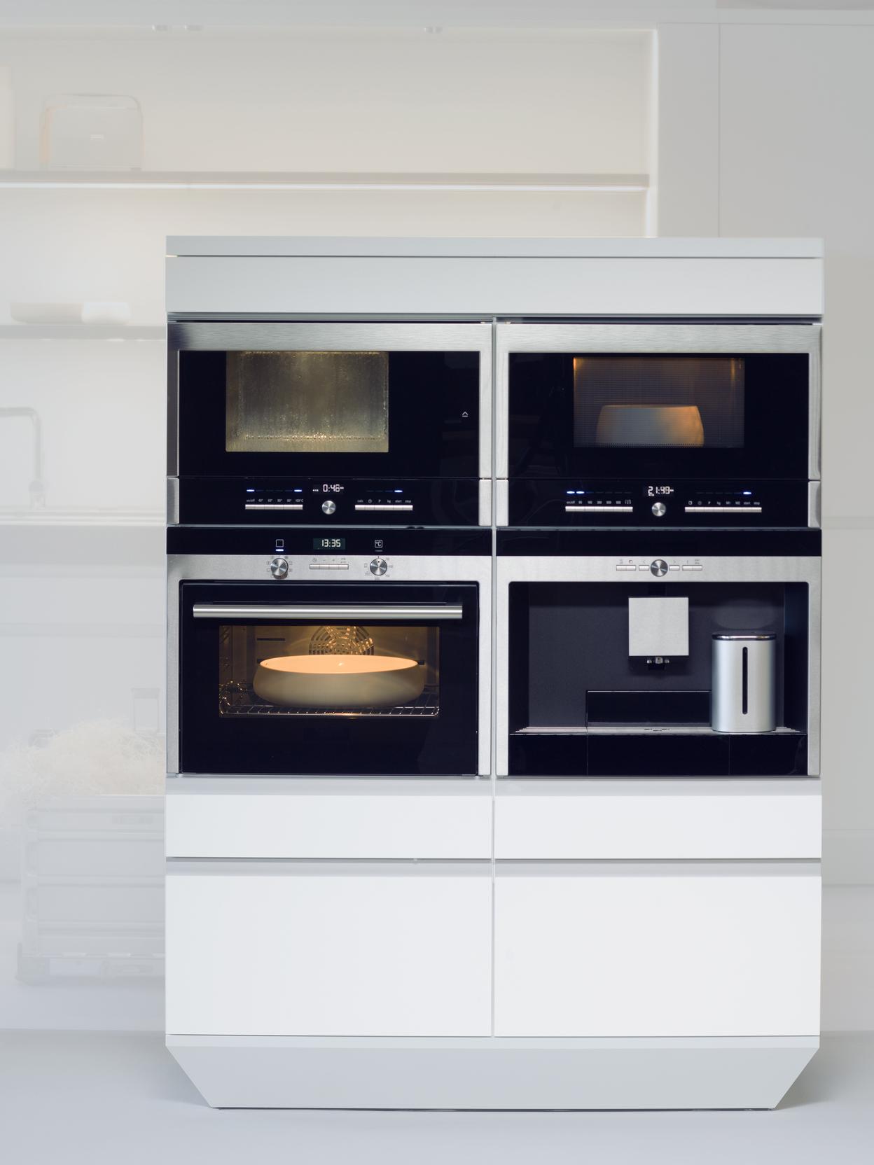 Moderne K&uuml;cheneinheit mit vier integrierten Ger&auml;ten: Mikrowelle, Dampfgarer, Backofen und Kaffeevollautomat.