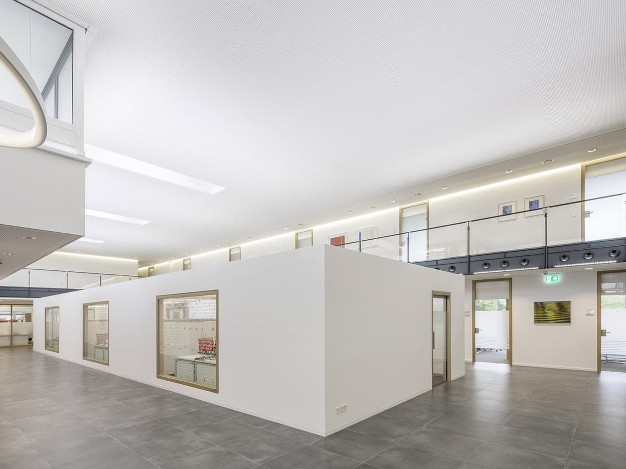 Moderne B&uuml;roeinrichtung mit offenen R&auml;umen, wei&szlig;en W&auml;nden und gro&szlig;en Fenstern in einem hellen, minimalistischen Stil.