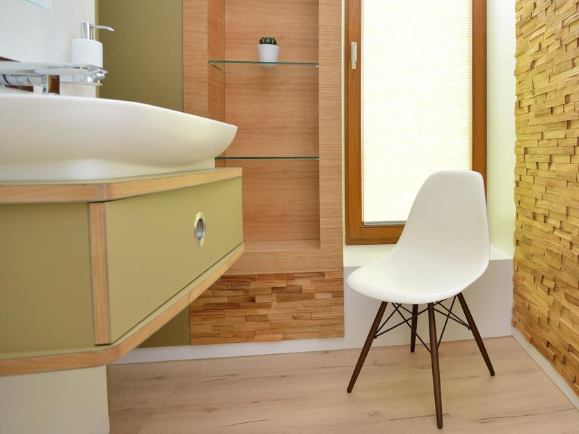 Helles Badezimmer mit Holzregal, Waschtisch und moderner wei&szlig;er Stuhlwand. Fenster mit Jalousien sorgt f&uuml;r Tageslicht.