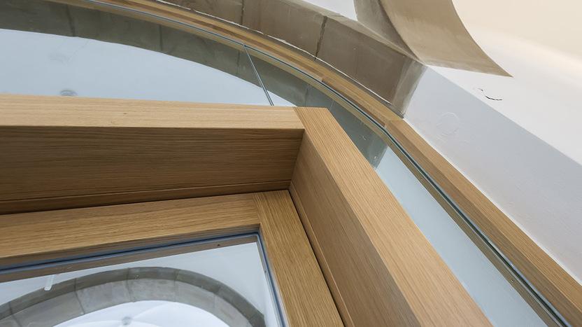 Detailaufnahme einer modernen Fensterkonstruktion aus Holz und Glas mit gew&ouml;lbter Form.