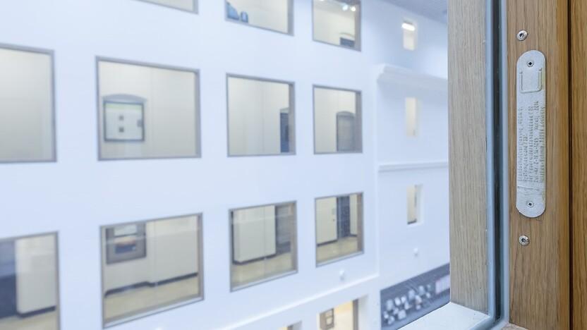 Blick aus einem Fenster auf einen Innenhof mit mehreren gro&szlig;en, rechteckigen Fenstern in einem modernen Geb&auml;ude.