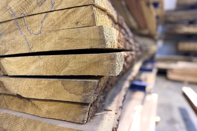 Nahaufnahme von gestapelten Holzbrettern mit sichtbaren Fugen und strukturierten Oberfl&auml;chen in einem Holzlager.