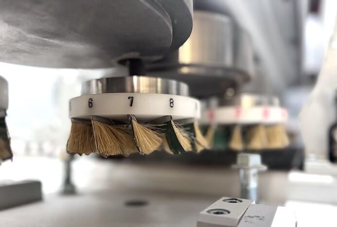 Nahaufnahme von rotierenden B&uuml;rsten an einer Maschinenvorrichtung zur Oberfl&auml;chenbearbeitung.